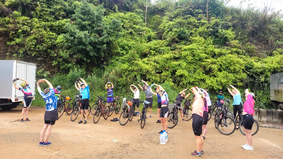 A cycling group warming up beside their bikes, their support truck parked by the roadside