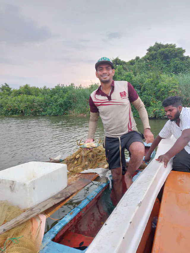 A lagoon fisherman holding up a mud crab from his outrigger canoe