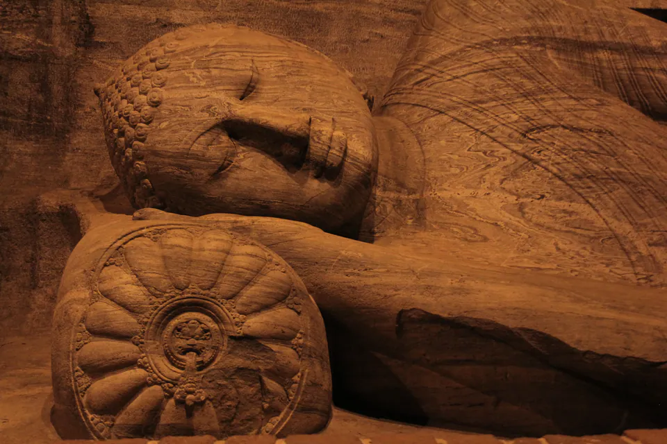 The serene face of the reclining Buddha at Gal Vihara resting on its carved lotus pillow