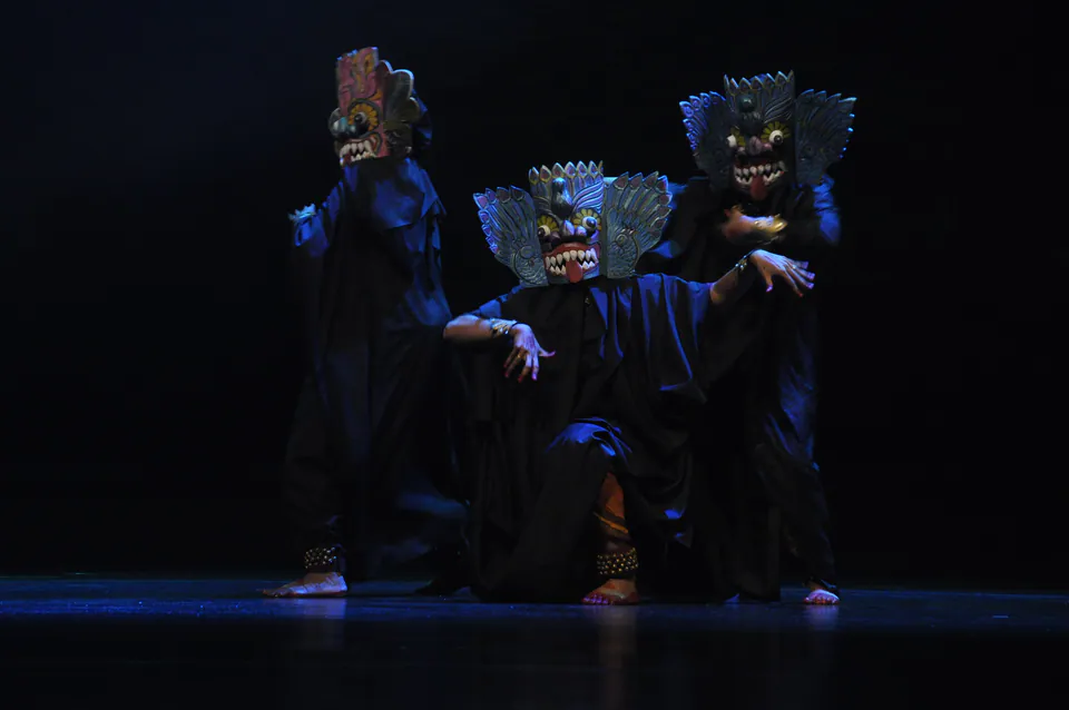 Dancers in carved and painted demon masks performing the devol yakku dance under blue stage light