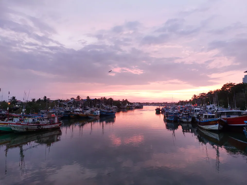 Fishing boats moored along a still channel under a pink dawn sky
