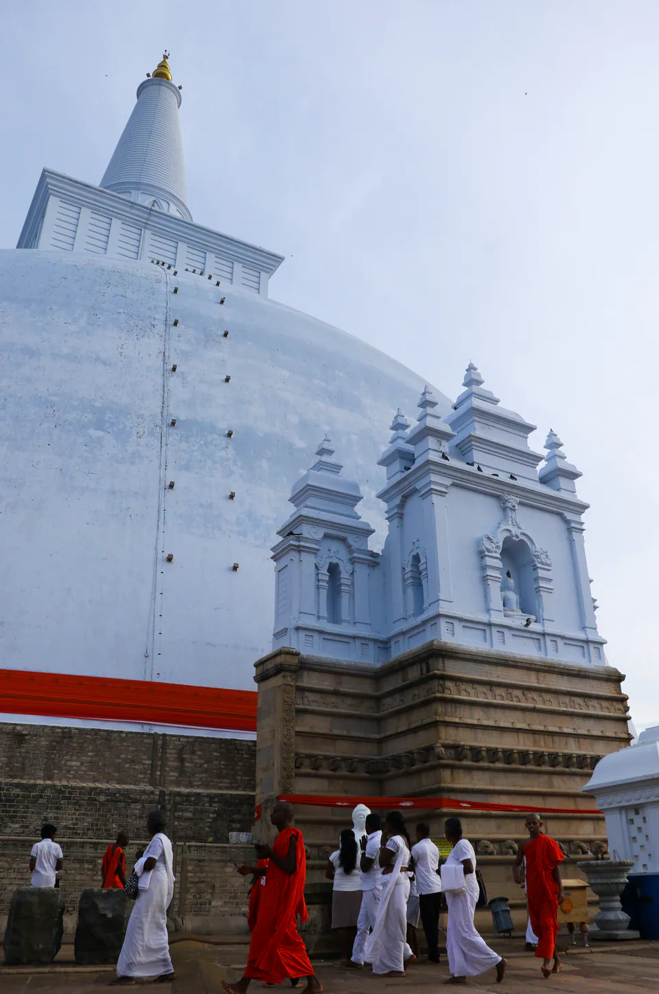 Pilgrims in white and monks in saffron walking beneath the great white dome of Ruwanwelisaya