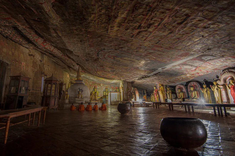 Monks seated in prayer beneath the painted rock ceiling of the Dambulla cave temple