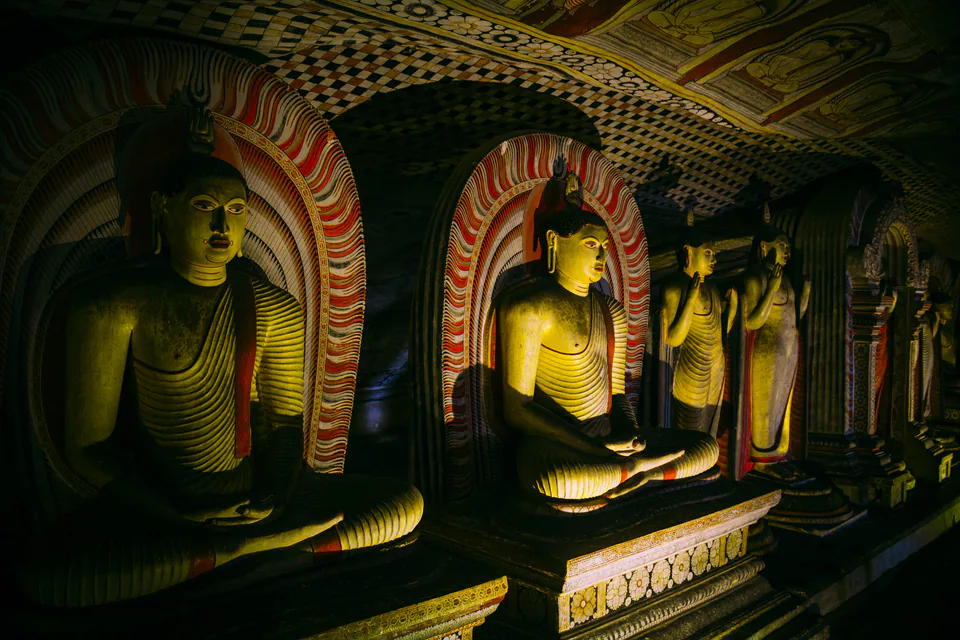 Painted Buddha statues beneath the frescoed rock ceiling of the Dambulla cave temple