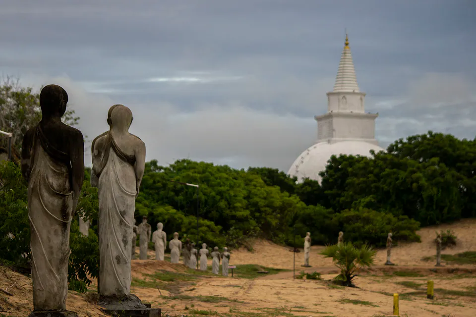 Ancient standing stone statues and a white dagoba among the sand dunes of Muhudu Maha Viharaya