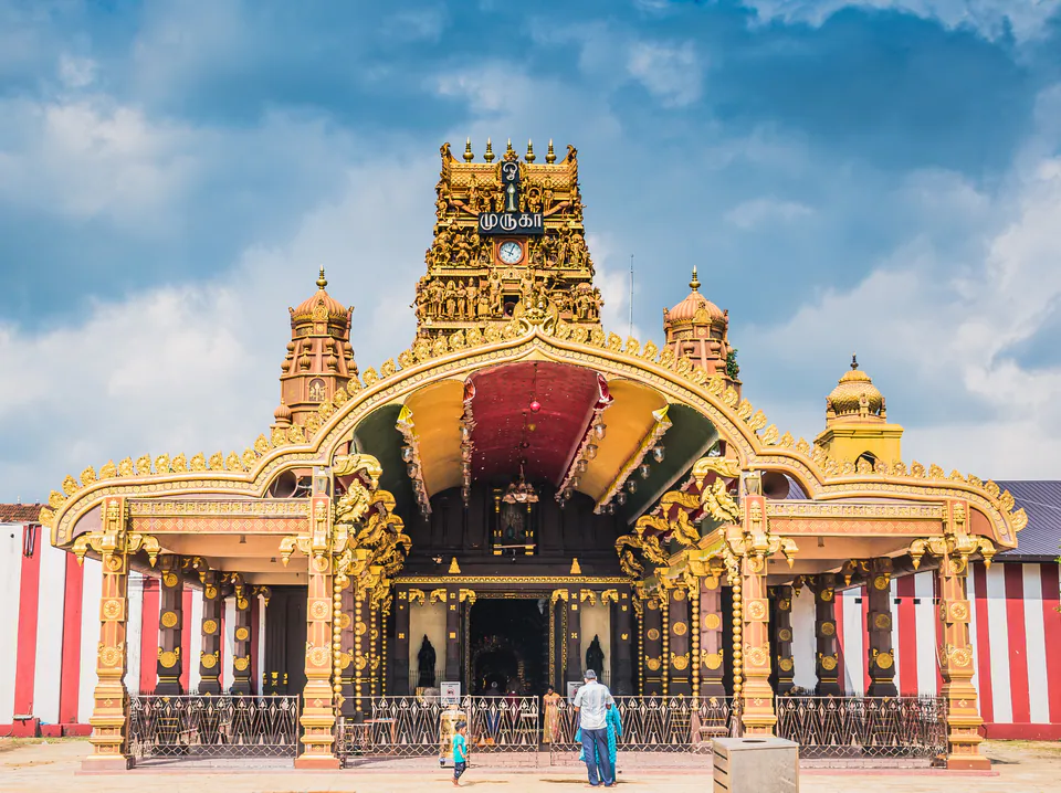 The golden entrance arch and tower of Nallur Kandaswamy Kovil against a blue sky