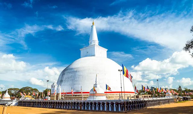 The great white Ruwanwelisaya dagoba with Buddhist flags under a blue sky