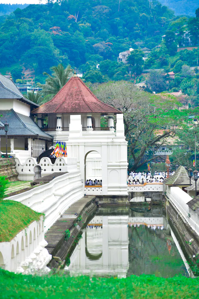 The octagon of the Temple of the Tooth reflected in its moat, worshippers in white