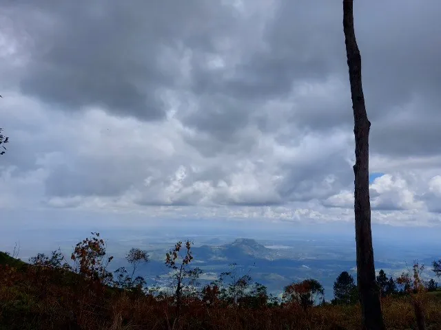 Dark rain clouds over the hazy lowland plain, seen from the escarpment edge